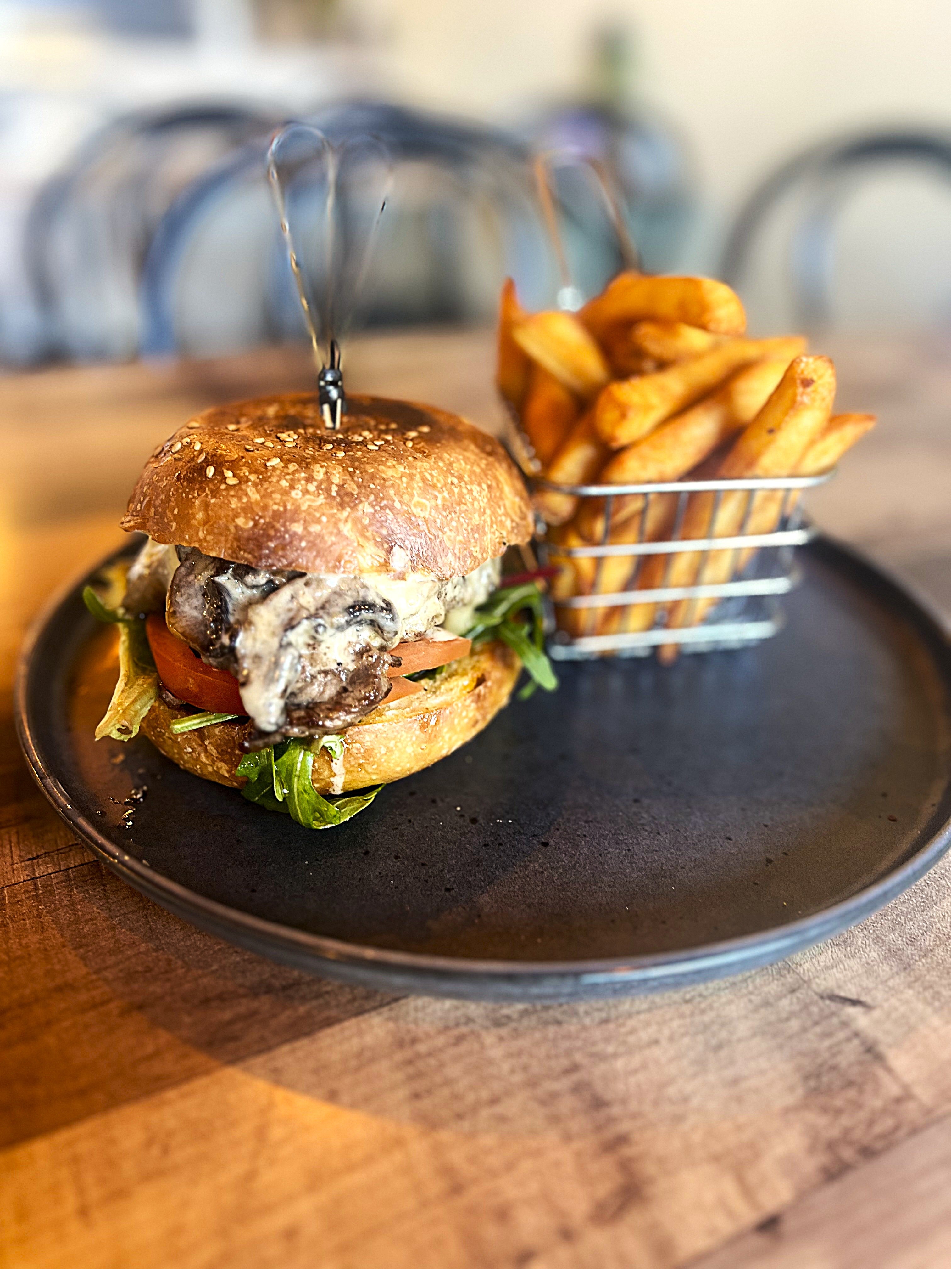 Hamburger and fries on a black plate with a blurred background